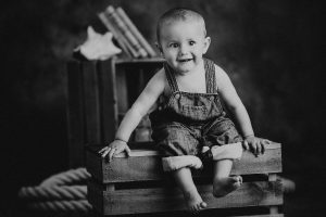 niño sentado sobre caja de madera en blanco y negro