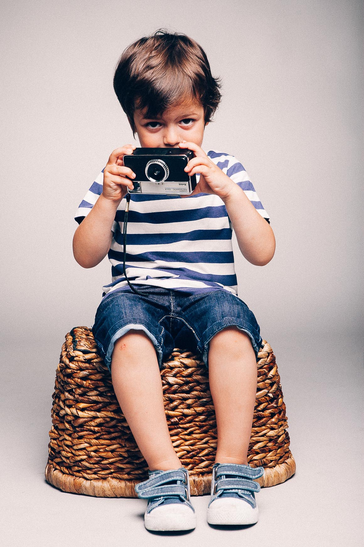 niño sentado con cámara de fotos mirando a fotógrafo