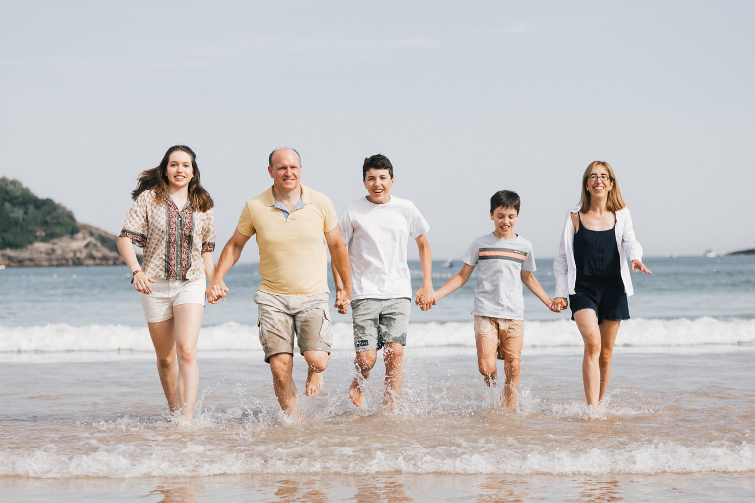 Family enjoying vacation photoshoot in the water in La Concha Beach, Donostia